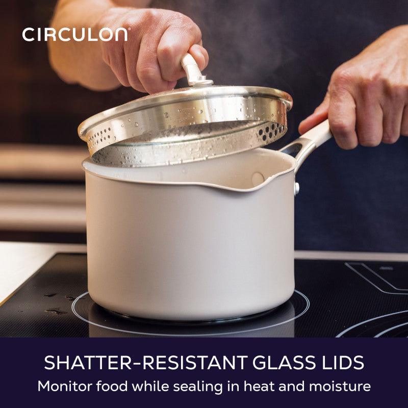 Shatter-resistant glass lids, monitor food while sealing in heat and moisture: hand lifting the glass straining lid off a taupe saucepan on a cooktop