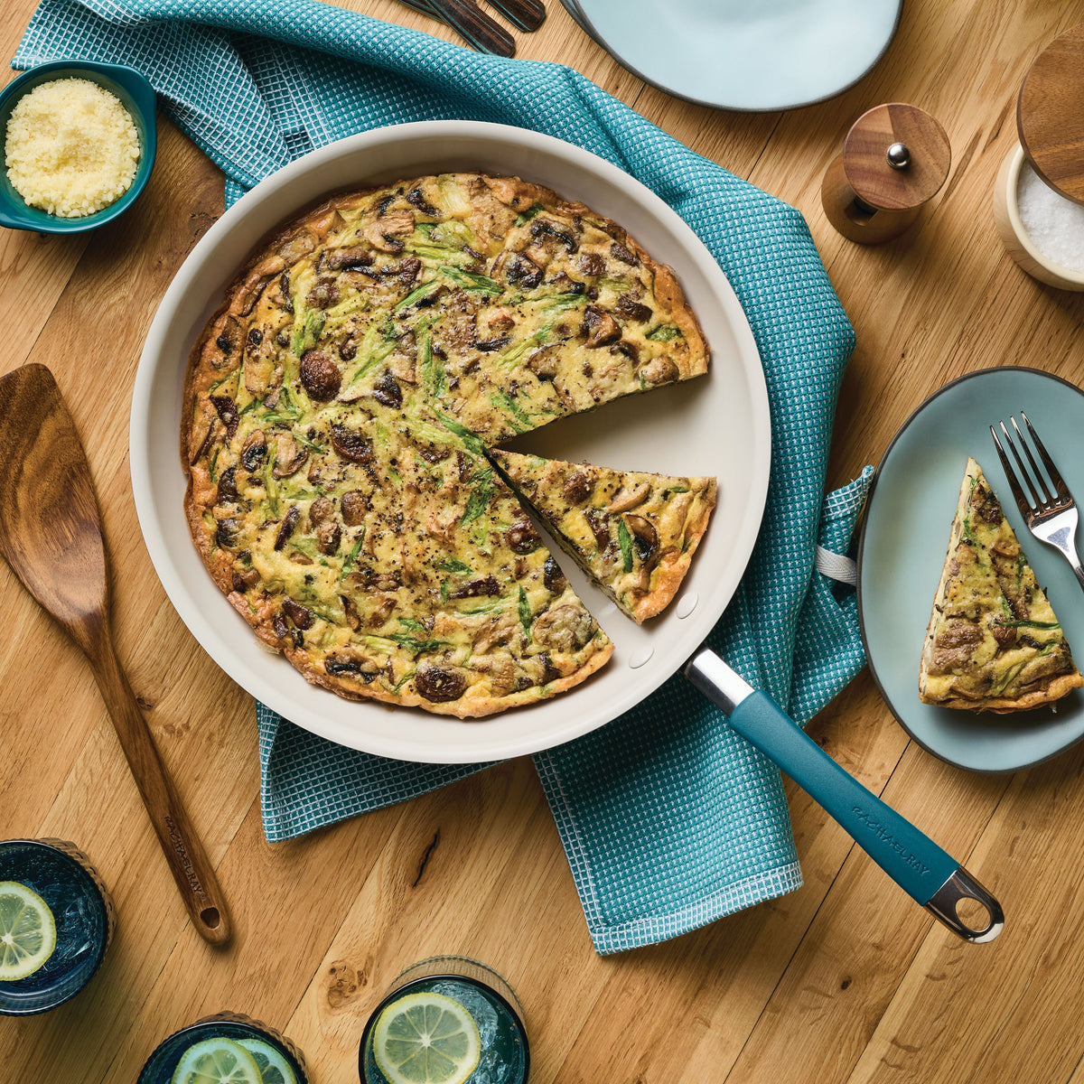 Top view of a marine blue frying pan holding a mushroom frittata with one slice cut out and served on a plate beside it