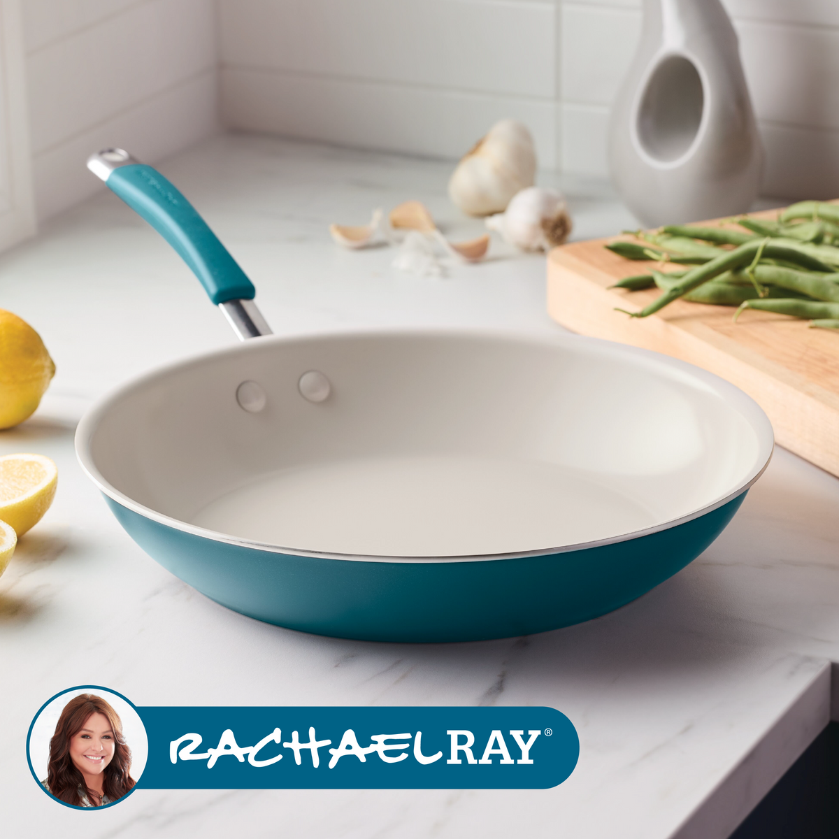 Marine blue ceramic nonstick frying pan on a marble counter with lemons, garlic and green beans, with the Rachael Ray logo