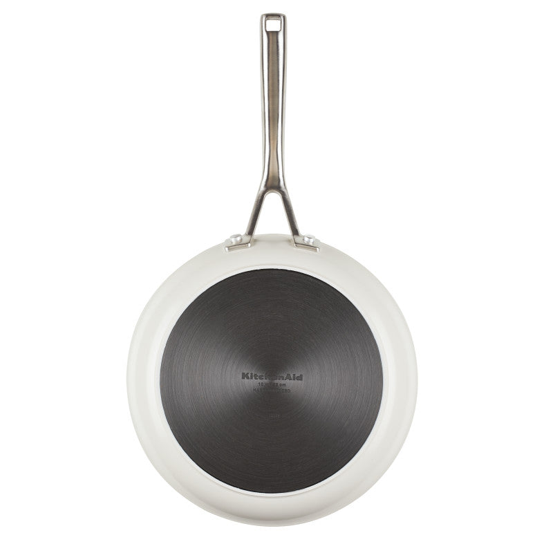 Bottom view of the porcelain white frying pan showing its dark hard anodized base with the KitchenAid stamp