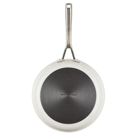 Bottom view of the porcelain white frying pan showing its dark hard anodized base with the KitchenAid stamp