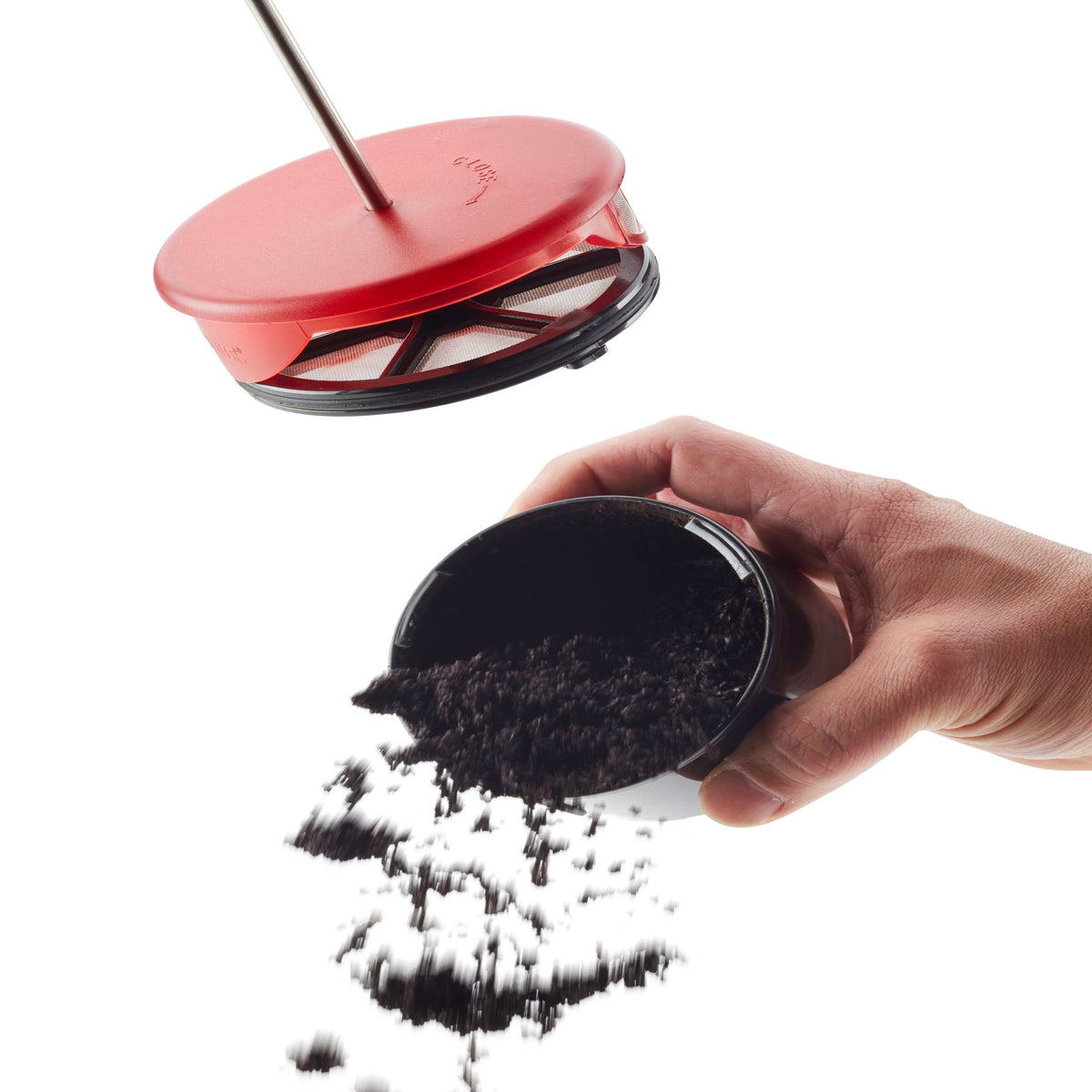 Hand tipping used coffee grounds out of the black filter cup below the red plunger lid